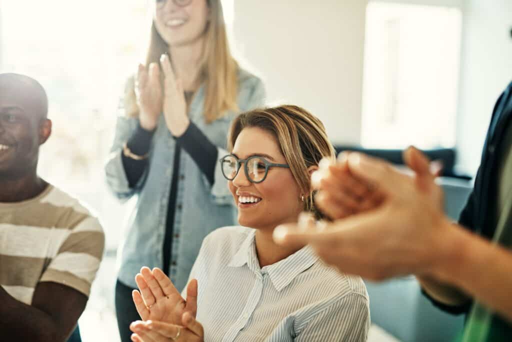 Smiling group of diverse colleagues clapping during an office meeting